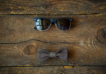 Sunglasses and bow tie on a wooden background - required items lifestyle modern businessmanの写真素材