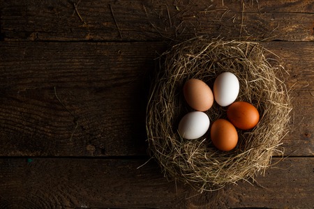 Fresh chicken eggs in a nest on a wooden rustic backgroundの写真素材