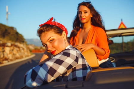 Two young happy girls having fun in the cabriolet outdoors, summer vacation concept