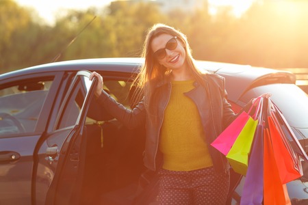Smiling Caucasian woman putting her shopping bags into the car - shopping conceptの写真素材