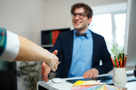Modern young business man with arm extended to handshakeの写真素材