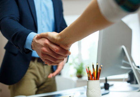 Young businessman and businesswoman shaking hands in officeの写真素材