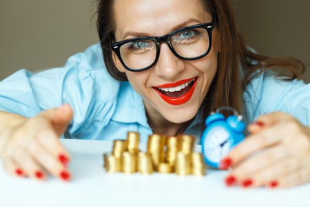 Saving, smiling woman stacking gold coins into columnsの写真素材