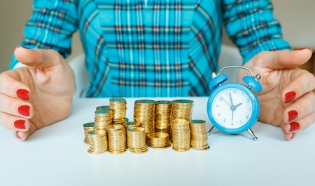 Protect new business start-up concept - with hand, coin and and blue alarm clockの写真素材