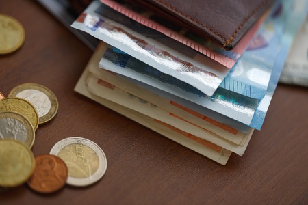 Brown leather wallet with euro money inside and coins, credit cards near itの写真素材