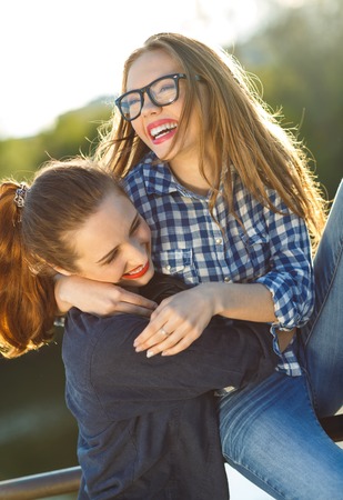 Two playful young women having fun outdoors at sunset lightの写真素材