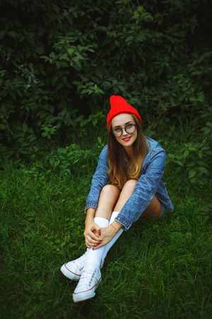 Beautiful young girl posing against the backdrop of the green grass and treesの写真素材