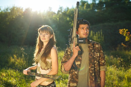 White young girl and an Arab man in camouflage with a weapon in the hands of outdoorsの写真素材