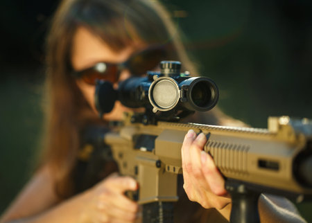 A young girl with a gun for trap shooting and shooting glasses aiming at a target