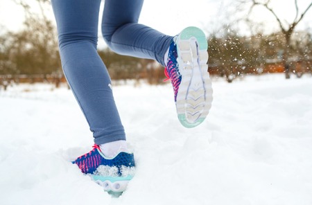 Running shoes - closeup of female sport fitness runner getting ready for jogging outdoors in winterの写真素材