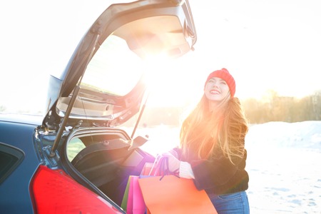 Smiling Caucasian woman putting her shopping bags into the car trunk - shopping conceptの写真素材