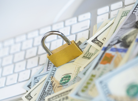 Security lock on dollar bills with white computer keyboard - breach of security online payments conceptの写真素材