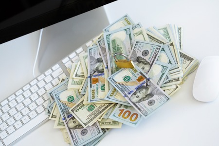 Security lock on dollar bills with white computer keyboard - breach of security online payments conceptの写真素材