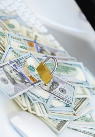 Security lock on dollar bills with white computer keyboard - breach of security online payments conceptの写真素材