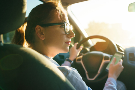 Woman uses a navigator in a smartphone while driving a carの写真素材
