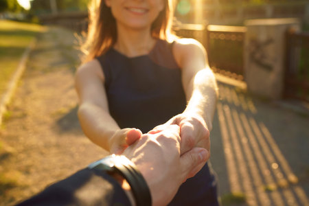 Follow me - happy young woman pulling guy's hand - hand in hand walking on a bright sunny day - concept of carefree modern lifeの写真素材