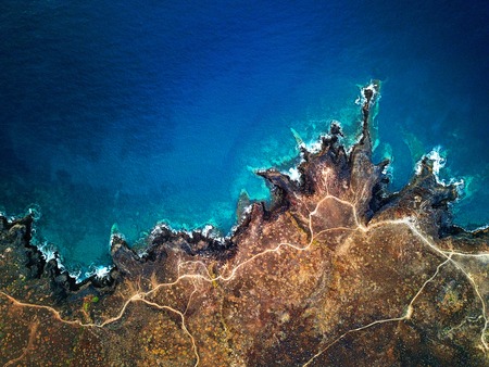 Top view of a deserted coast. Rocky shore of the island of Tenerife, Canary Islands, Spain. Aerial drone footage of sea waves reaching shoreの写真素材