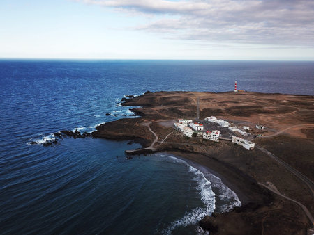 Aerial view of rocky coastline with white buildings and a lighthouse on Tenerife, Canary Islands,...