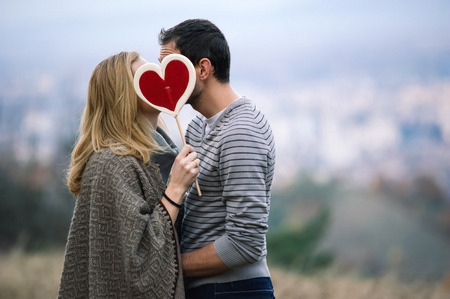 Young couple kissing and holding a candy heartの写真素材