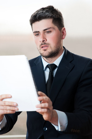 Handsome business man looking over a clipboardの写真素材