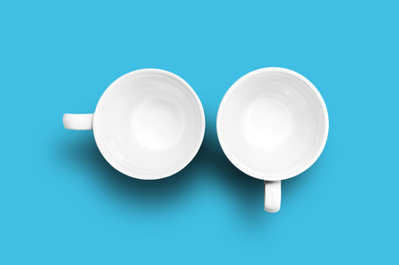 Two empty cups on blue background. Studio shotの写真素材