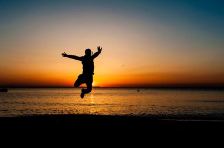 Silhouette of jumping man on sunrise backgroundの写真素材