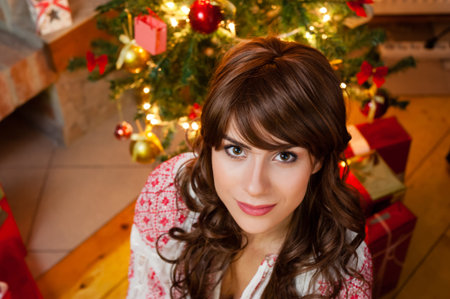 Portrait of smiling young woman near christmas tree over living room.