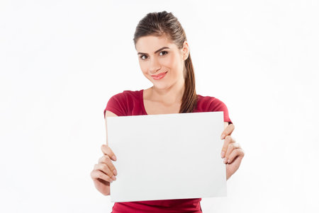 Girl hold white blank paper. Young smiling woman show blank card. Girl portrait isolated on white background.の写真素材