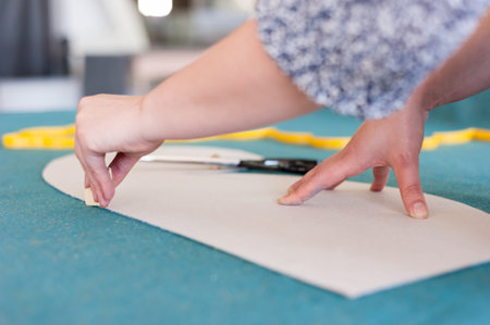 Female fashion designer working with sketches at studio and choosing cloth