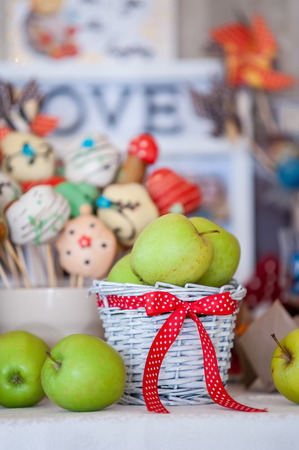 Green apples in basket with red ribbon. Party decoration.の写真素材