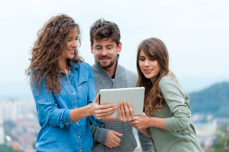Three Friends looking at digital tablet, outdoors - friendship, technology concept.