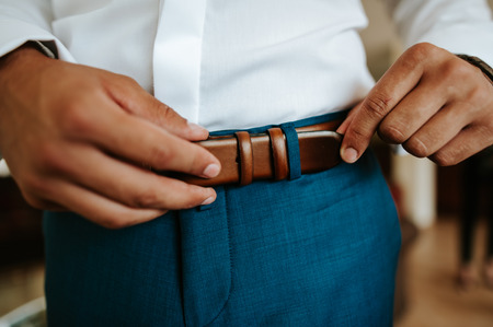 Close-up of a businessman putting on beltの写真素材