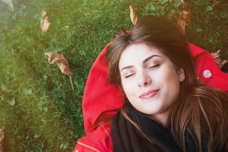 Close-up and top view of woman sitting in the green grass with her eyes closed.の写真素材