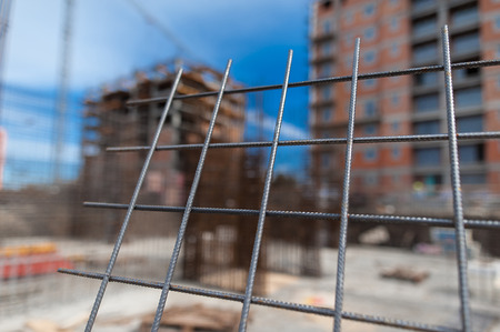 Reinforcement net of concrete in the construction site, metal rods for strength with a building under construction on the backgroundの写真素材