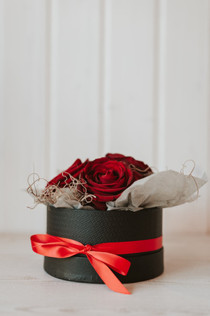 Vertical picture of romantic luxury red roses in a black gift box with red ribbon.の写真素材