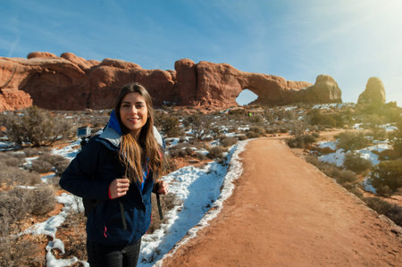 Beautiful woman hiking along a scenic canyon overlook in Arches National Park in Utah