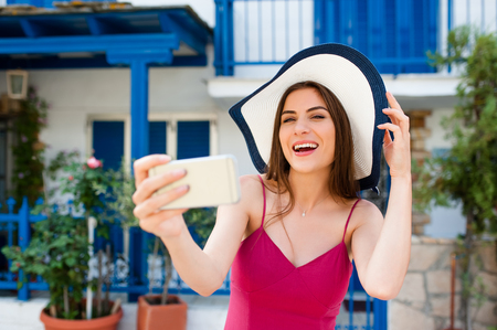 Europe travel selfie, cute happy smiling tourist girl taking self-portrait picture with smartphone during summer vacation in famous European destination, Greece.の写真素材