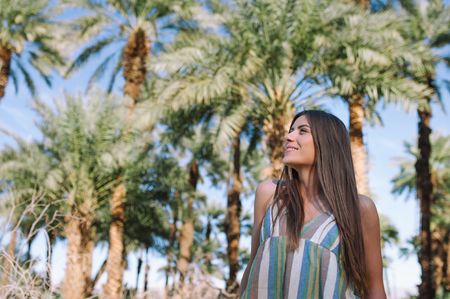 Holidays woman smiling on tropical beach summer vacation with palm trees and date palmsの写真素材
