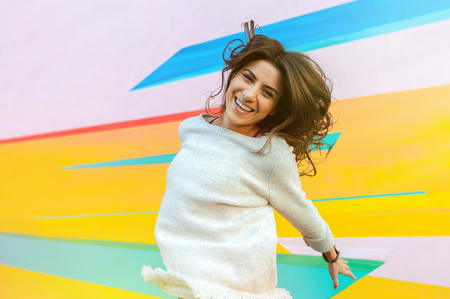 Joyful young woman on the street jumping on air looking happy and enjoying the time outdoor.の写真素材