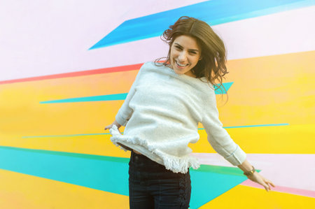 Joyful young woman on the street jumping on air looking happy and enjoying the time outdoor.