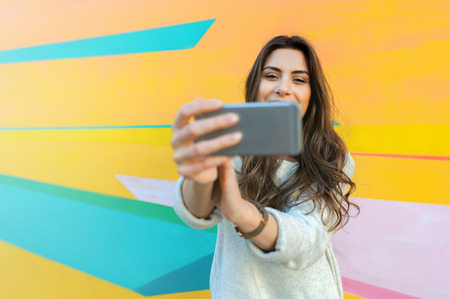 Hipster woman taking selfie photos in colorful abstract backgroundの写真素材