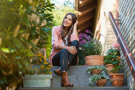 Relaxed young female smiling and looking at camera, sitting on home terrace. Hobby and resting leisure concept.の写真素材