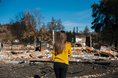 Young owner woman checking burned and ruined house and yard after fire, consequences of fire disaster accident. Ruins after fire disaster, loss and despair concept.の写真素材