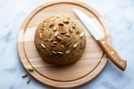 Homemade bread with pumpkin seeds on the board. Round bread on the table. Baking at the bakery....