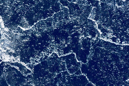 Ice texture with frozen bubbles and cracks on a dark blue background. Beautiful abstract decorative background. Stylish abstract design for wraps, gift, fabric, textile, furnishing. Winter pattern.の写真素材