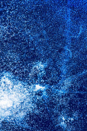 Ice texture with frozen bubbles and cracks on a dark blue background. Beautiful abstract decorative background. Stylish abstract design for wraps, gift, fabric, textile, furnishing. Winter pattern.の写真素材
