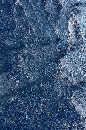Ice texture with frozen bubbles and cracks on a dark blue background. Beautiful abstract decorative background. Stylish abstract design for wraps, gift, fabric, textile, furnishing. Winter pattern.の写真素材