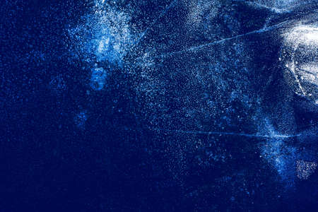 Ice texture with frozen bubbles and cracks on a dark blue background. Beautiful abstract decorative background. Stylish abstract design for wraps, gift, fabric, textile, furnishing. Winter pattern.の写真素材