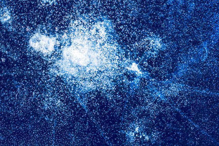 Ice texture with frozen bubbles and cracks on a dark blue background. Beautiful abstract decorative background. Stylish abstract design for wraps, gift, fabric, textile, furnishing. Winter pattern.の写真素材