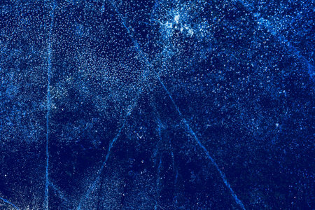 Ice texture with frozen bubbles and cracks on a dark blue background. Beautiful abstract decorative...